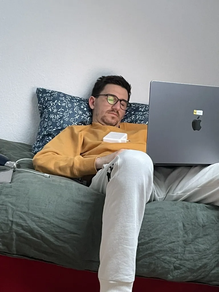 Teammitglied eingeschlafen mit Laptop und Ladegerät auf dem Sofa