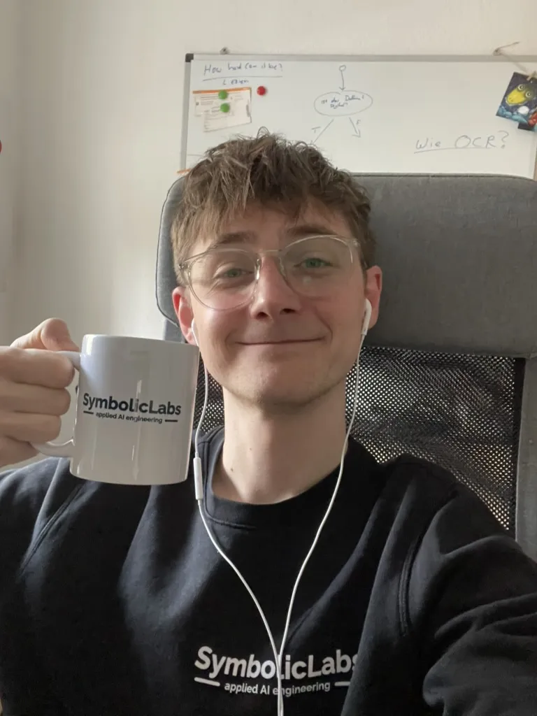 Teammitglied mit SymbolicLabs Tasse vor einem Whiteboard voller Skizzen